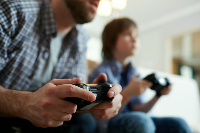 Een volwassene en kind spelen samen een videogame